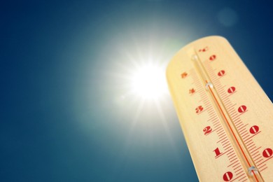 Image of Thermometer showing high temperature against sky with bright sun. Extremely hot weather