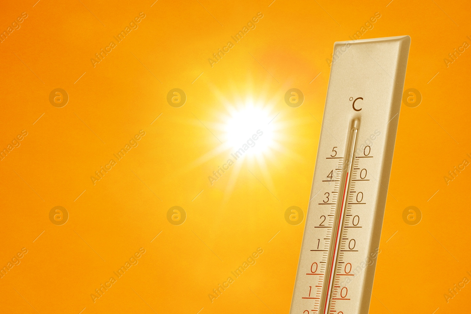 Image of Thermometer showing high temperature against orange sky with bright sun. Extremely hot weather