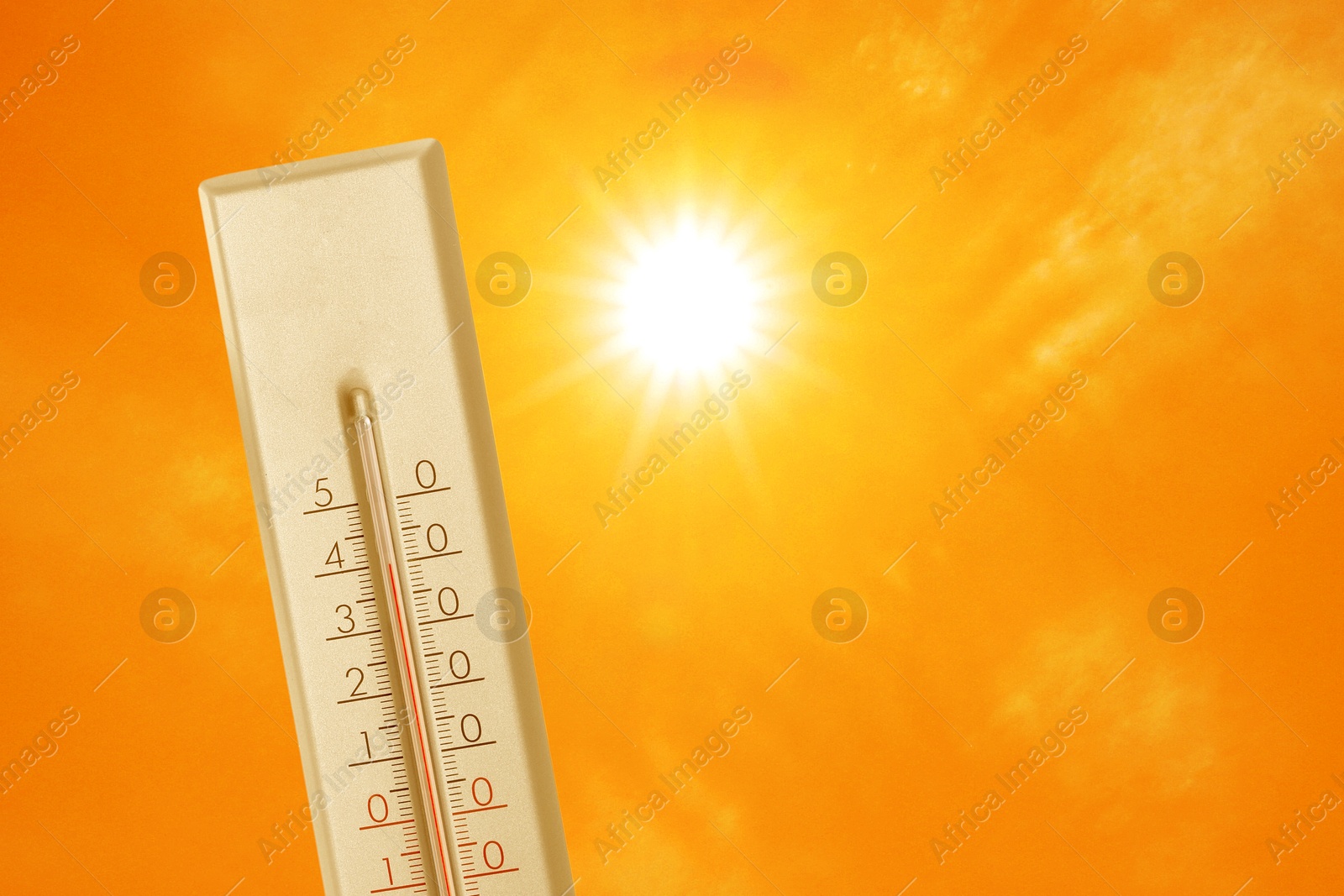 Image of Thermometer showing high temperature against orange sky with bright sun. Extremely hot weather