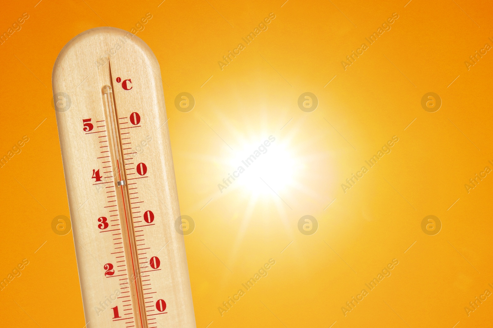 Image of Thermometer showing high temperature against orange sky with bright sun. Extremely hot weather