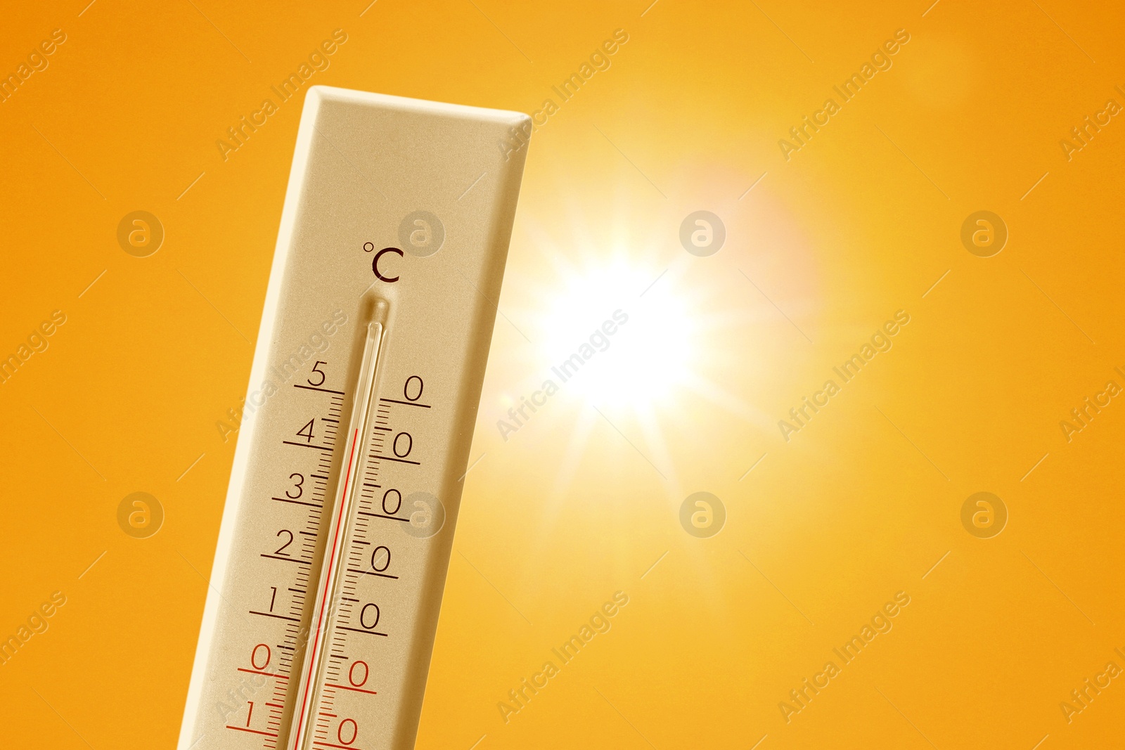 Image of Thermometer showing high temperature against orange sky with bright sun. Extremely hot weather