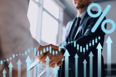 Image of Business partners shaking hands, closeup. Percent sign, arrows and graph