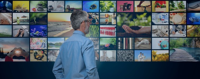 Image of Media library. Man in front of collection of video files on virtual screen against dark background