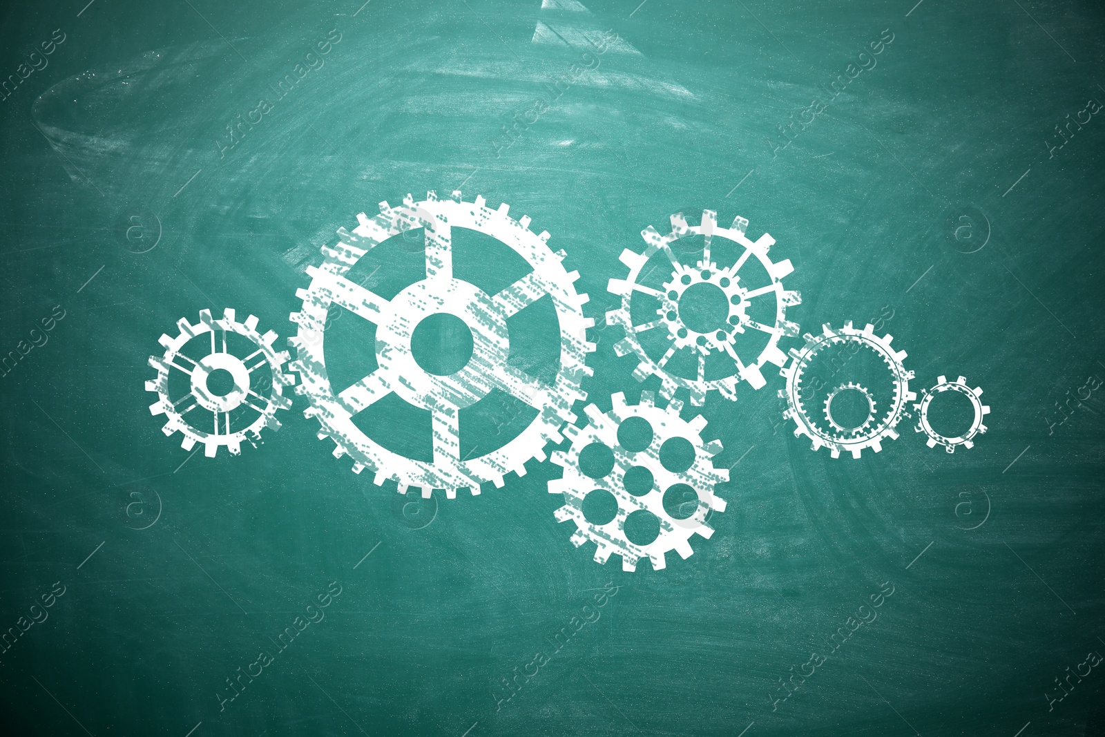 Image of Many cogwheels drawn on green chalkboard. Gear mechanism