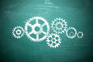 Image of Many cogwheels drawn on green chalkboard. Gear mechanism