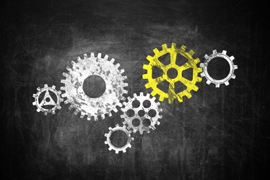 Image of Many cogwheels drawn on black chalkboard. Gear mechanism