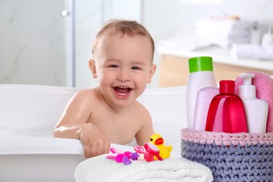 Image of Cute little baby in bathtub, accessories and toiletries indoors
