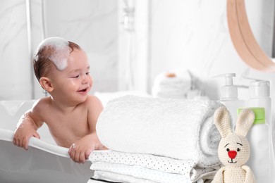 Image of Cute little baby in bathtub, accessories and toiletries indoors