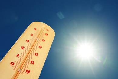 Image of Thermometer showing high temperature against sky with bright sun. Extremely hot weather