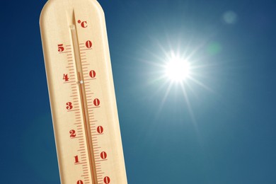 Image of Thermometer showing high temperature against sky with bright sun. Extremely hot weather