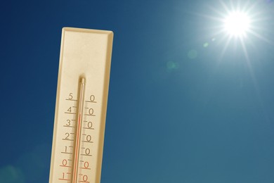 Image of Thermometer showing high temperature against sky with bright sun. Extremely hot weather