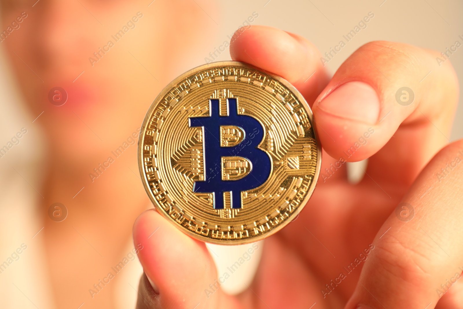 Photo of Cryptocurrency. Man holding golden bitcoin against blurred grey background, closeup