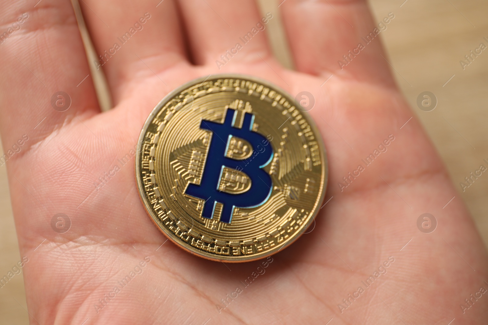 Photo of Cryptocurrency. Man with golden bitcoin at table, closeup