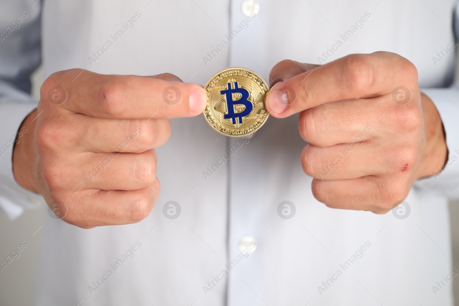 Photo of Cryptocurrency. Man with golden bitcoin, closeup view