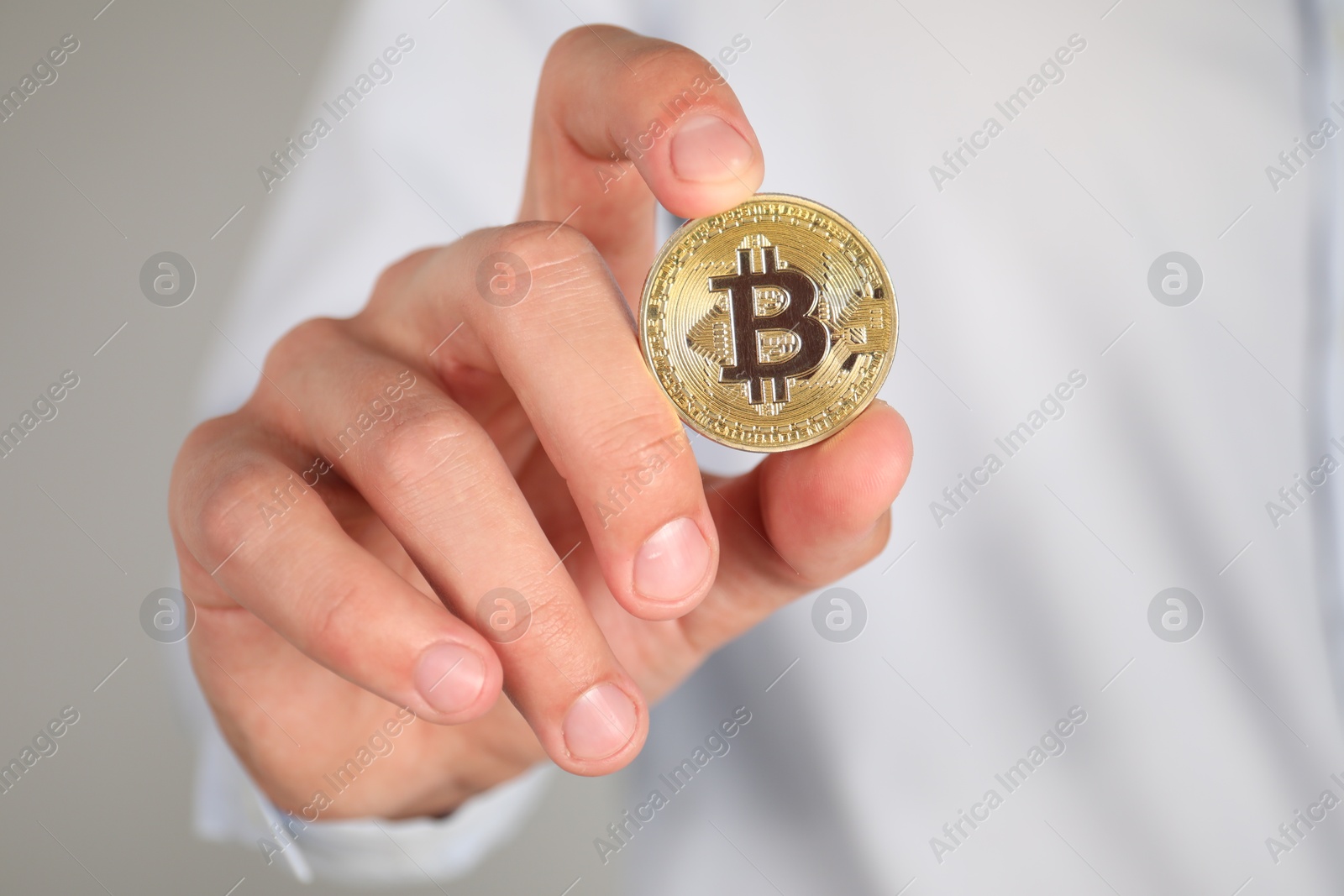 Photo of Cryptocurrency. Man with golden bitcoin on grey background, closeup