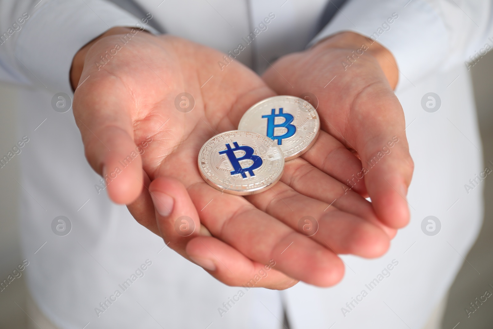 Photo of Cryptocurrency. Man with silver bitcoins on blurred background, closeup