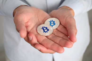 Photo of Cryptocurrency. Man with silver bitcoins on blurred background, closeup