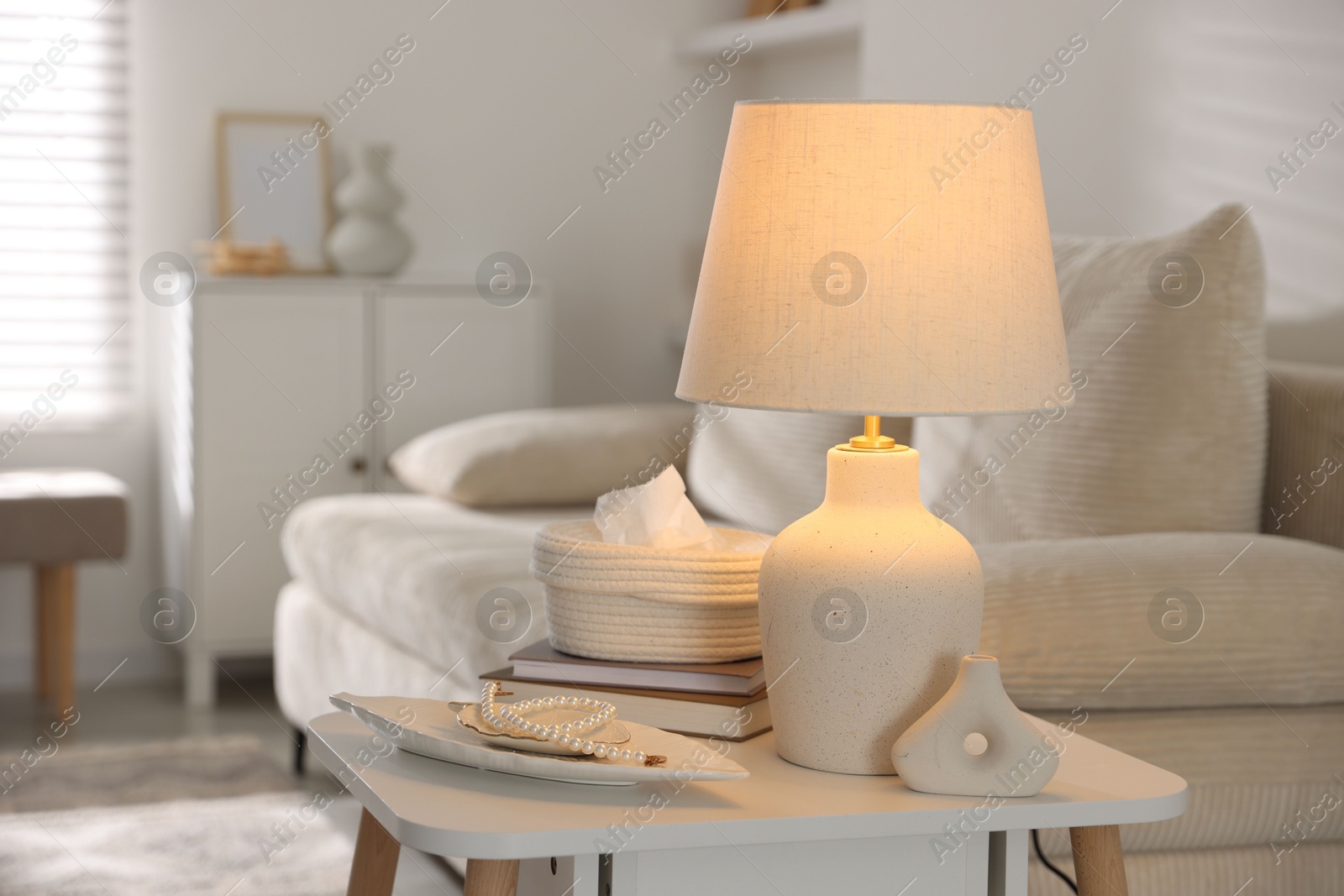 Photo of Stylish lamp, decor and book on white table indoors