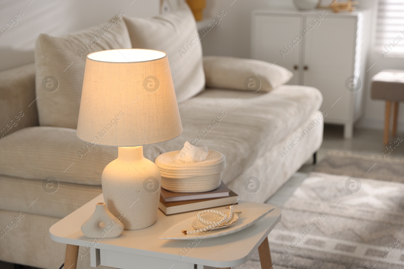 Photo of Stylish lamp, decor and book on white table indoors