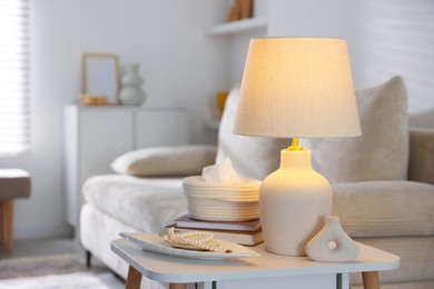 Photo of Stylish lamp, decor and book on white table indoors