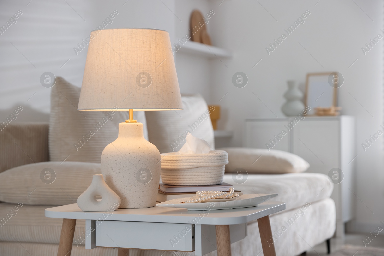 Photo of Stylish lamp, decor and book on white table indoors