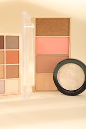 Photo of Eyeshadow palettes and pan on beige background with shadows, closeup