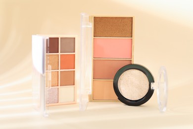 Photo of Eyeshadow palettes and pan on beige background with shadows, closeup