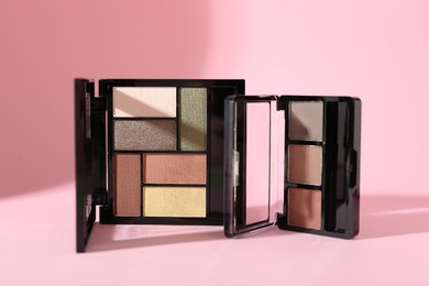 Photo of Colorful eyeshadow palettes on pink background with shadows, closeup