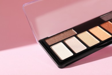 Photo of Colorful eyeshadow palette on pink background with shadows, closeup. Space for text