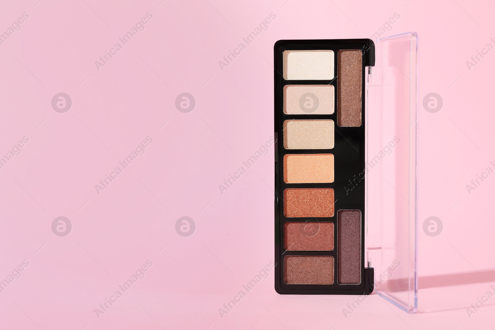 Photo of Colorful eyeshadow palette on pink background, closeup. Space for text