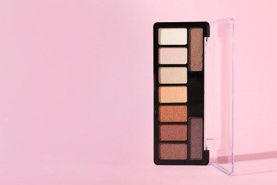 Photo of Colorful eyeshadow palette on pink background, closeup. Space for text