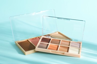 Photo of Colorful eyeshadow palettes on turquoise background, closeup