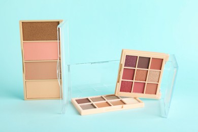 Photo of Colorful eyeshadow palettes on turquoise background, closeup