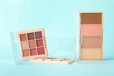 Photo of Colorful eyeshadow palettes on turquoise background, closeup