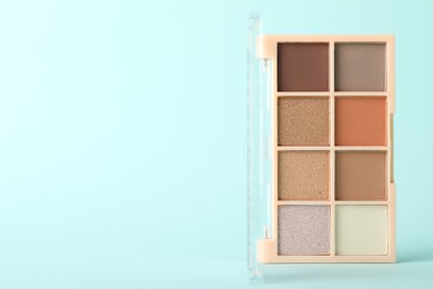 Photo of Colorful eyeshadow palette on turquoise background, closeup. Space for text