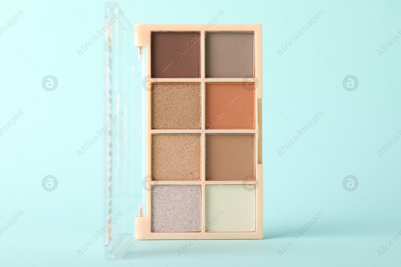 Photo of Colorful eyeshadow palette on turquoise background, closeup