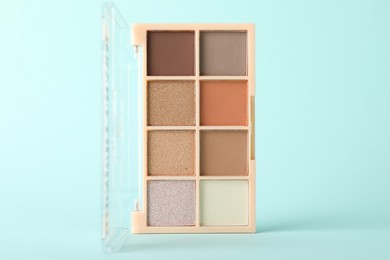 Photo of Colorful eyeshadow palette on turquoise background, closeup