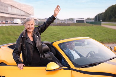 Photo of Stylish woman getting out of modern cabriolet outdoors