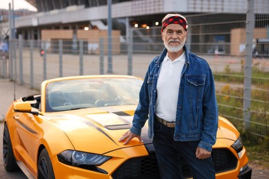 Photo of Stylish senior man near modern cabriolet outdoors