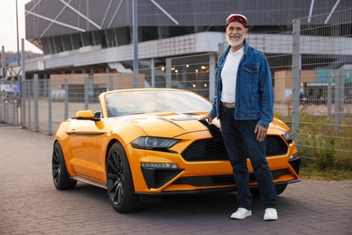 Photo of Stylish senior man near modern cabriolet outdoors