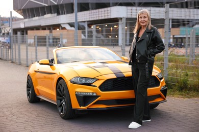 Photo of Stylish senior woman near modern cabriolet outdoors