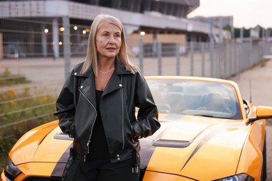 Photo of Stylish senior woman near modern cabriolet outdoors