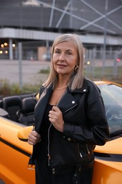 Photo of Stylish senior woman near modern cabriolet outdoors