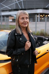 Photo of Stylish senior woman near modern cabriolet outdoors