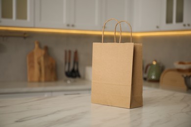 Photo of Paper bag on white marble table in kitchen. Space for text