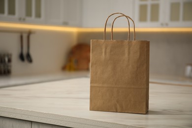 Photo of Paper bag on white marble table in kitchen. Space for text