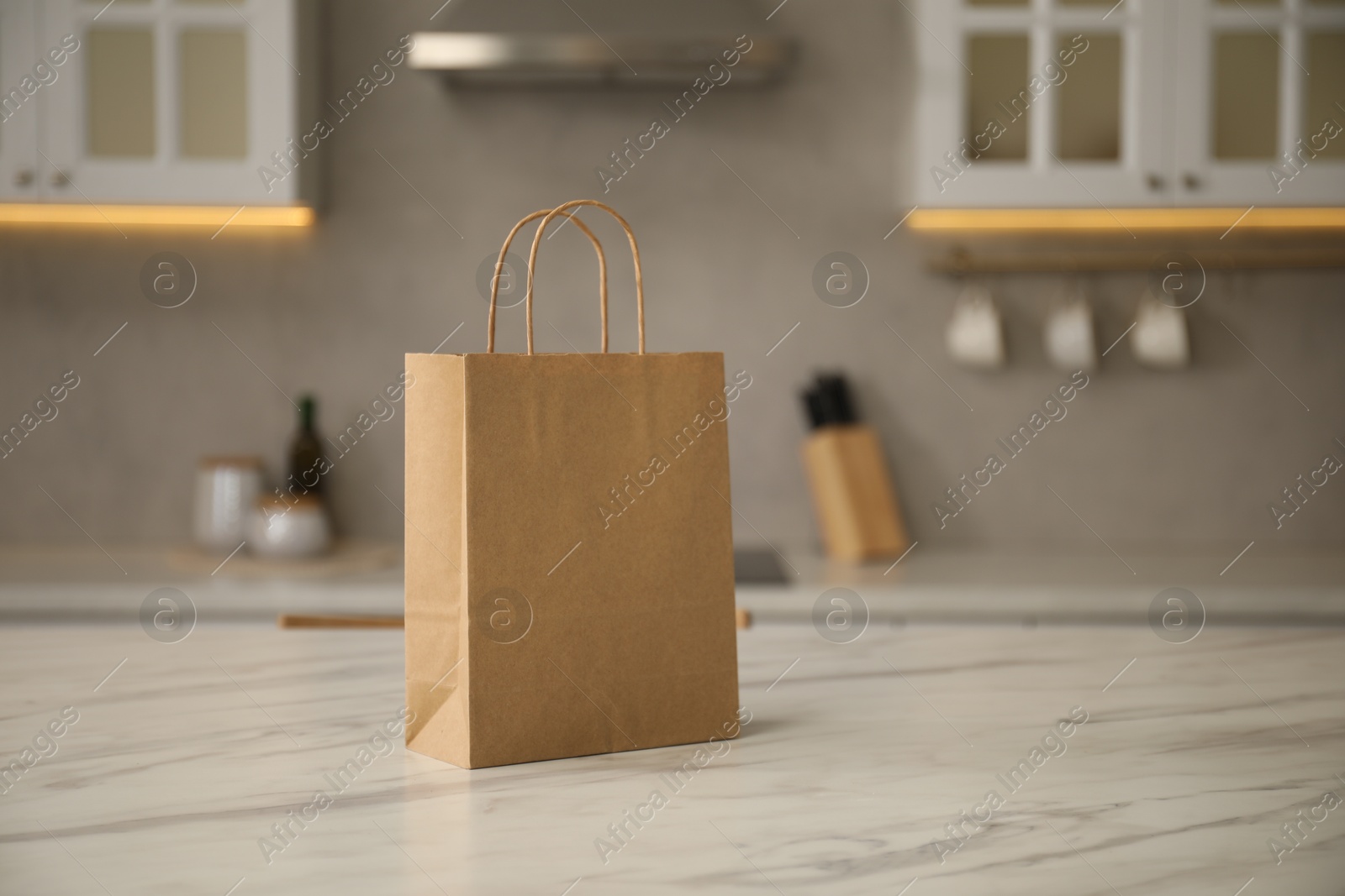 Photo of Paper bag on white marble table in kitchen. Space for text
