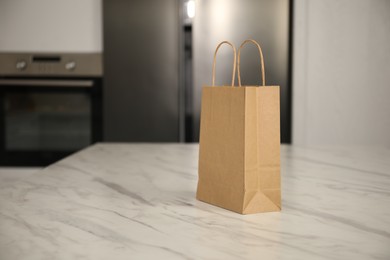 Photo of Paper bag on white marble table in kitchen. Space for text