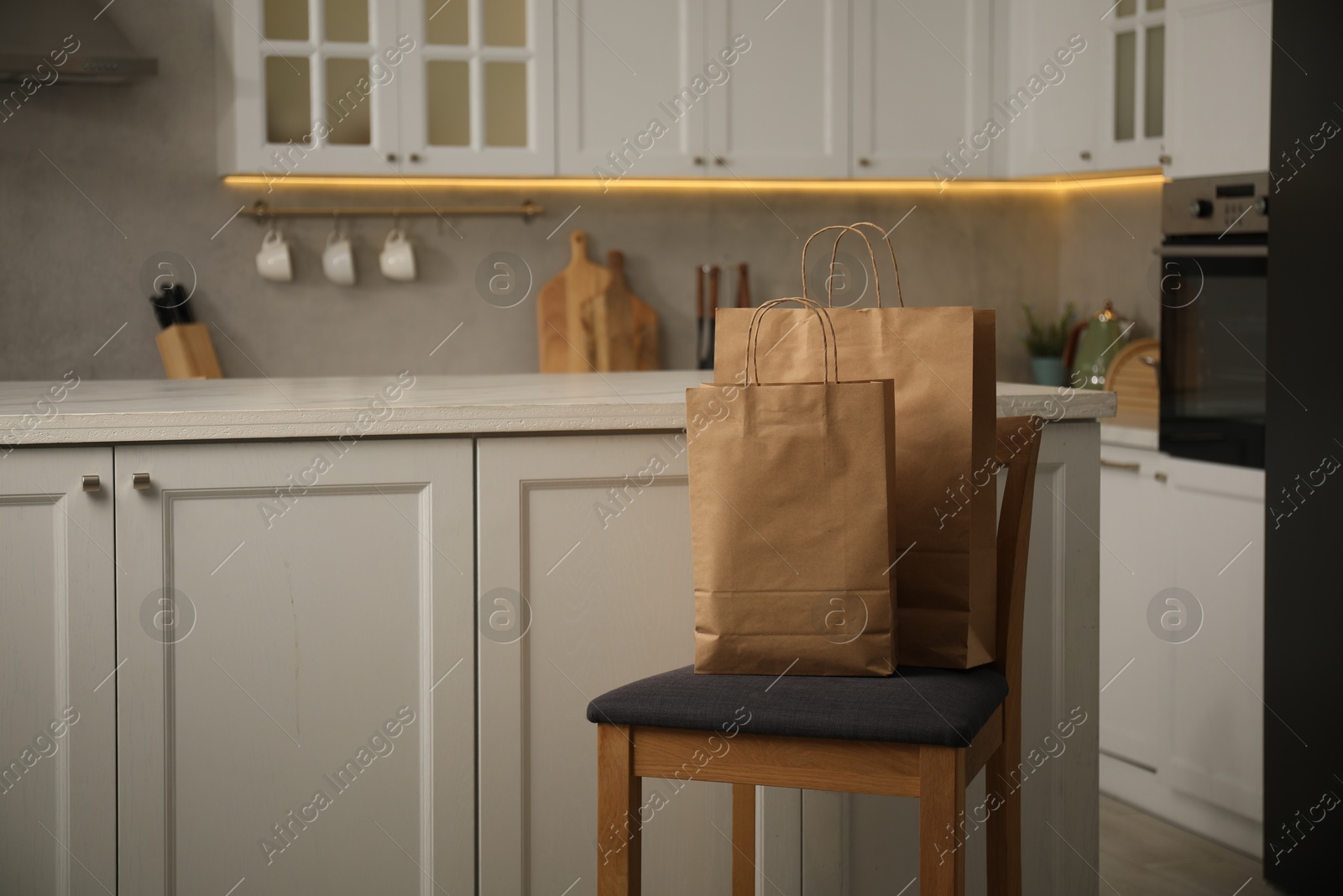 Photo of Paper bags on chair in kitchen. Space for text