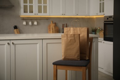 Photo of Paper bags on chair in kitchen. Space for text